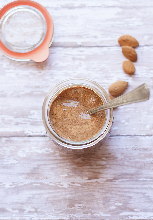 snickerdoodle almond butter with spoon, lid and almonds